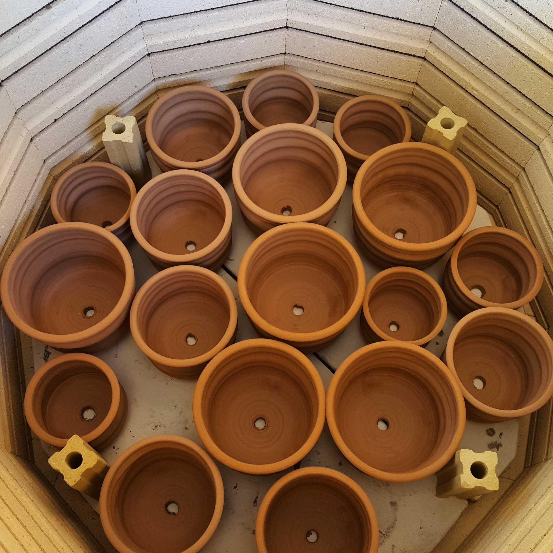 Terracotta planters arranged inside a kiln before firing